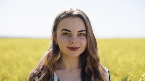 Portrait Pretty Girl Looking Into the Camera in the Rape Field. Young Woman Standing in the Rape's
