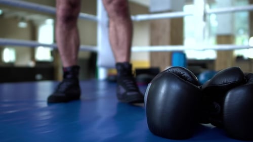 Boxer picks up black boxing gloves in boxing ring