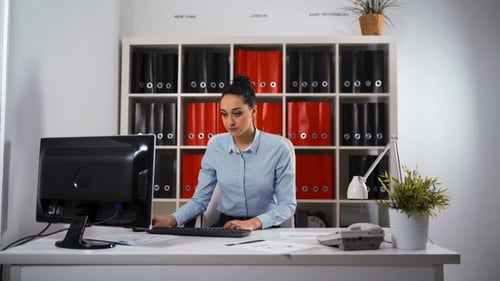 Young Woman Typing at Computer in Bright Office