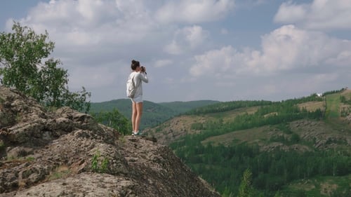 Woman Photographer Takes a Picture of a Mountain Landscape on the Camera