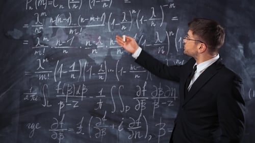 Mathematics Professor Explaining Equations on Blackboard