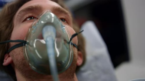 Homme blessé portant un masque à oxygène allongé sur des civières dans une ambulance