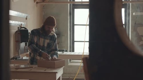 Man Working on Wooden Box in Workshop