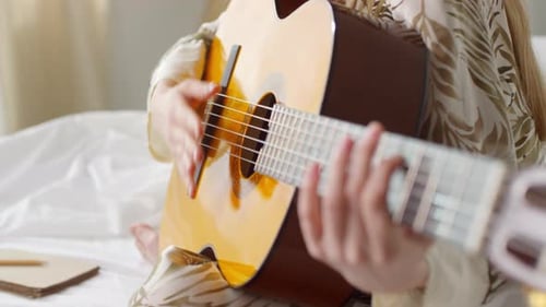 Young Woman Playing Acoustic Guitar at Home