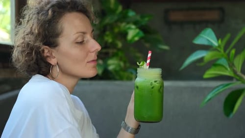 Portrait of Beautiful Curly Woman Drinking Refreshing Healthy Green Smoothie for Weight Loss and