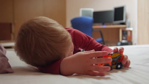 Cute Toddler Lying Down Playing with Toy Tractor