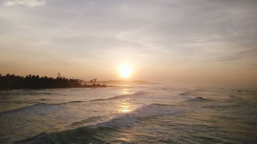 Drone Flying Forward Above Epic Sunset Ocean Coastline. Amazing Aerial Panorama of Waves Reaching