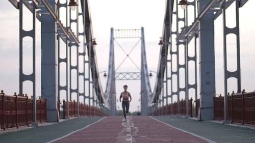 Fitness Female Jogging at Sunrise on Bridge