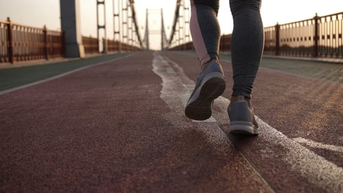 Female Legs Jogging at Sunrise on Bridge
