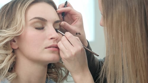 Visagistin trägt Wimpern-Make-up auf Model Eye auf