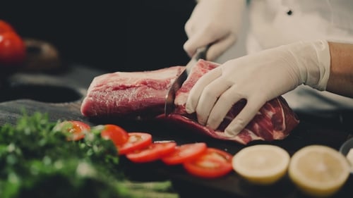 Chef Cutting Raw Meat in Kitchen