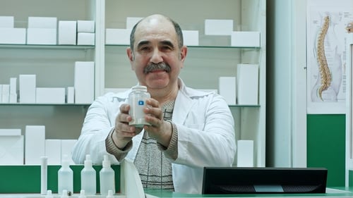 Friendly Doctor Holding Bottle of Pills and Smiling