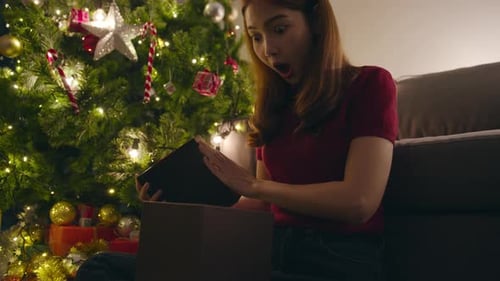 Excited Woman Opens Christmas Gift at Home