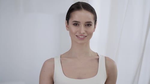 Beautiful Young Woman Smiles and Touches Her Face