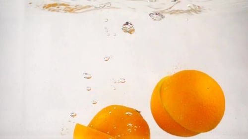 Las naranjas cortadas se hunden rápidamente en el agua con burbujas