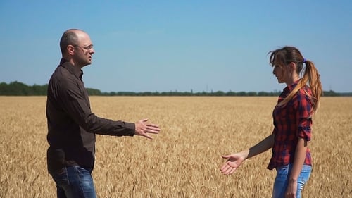 Two Farmers Shake Hands on Background of Field of Barley and Diverge in Different Directions