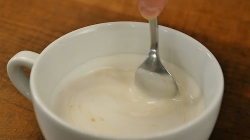 Mixing Liquid in White Mug with Spoon