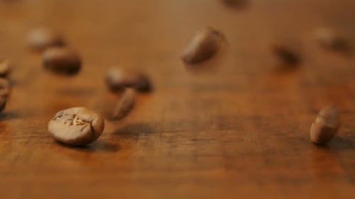 Kaffeebohnen fallen auf den Holztisch