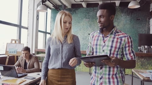 Two Colleagues Walking Through the Modern Office and Talking. African Man and Caucasian Woman
