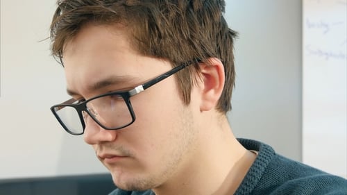 Young Male College Student Working on His Laptop Computer in a Classroom