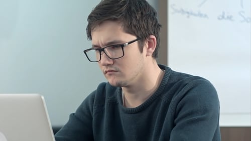 Young Pensive Student Working on Laptop at Home Office or Library with Serious Face