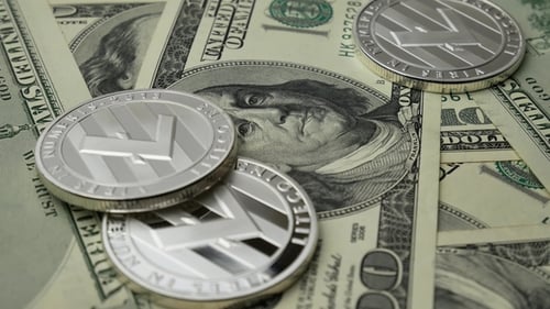 Pièces Litecoin LTC tournant sur des billets de 100 dollars