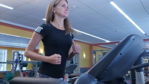 Active Young Woman Running on Treadmill in Sport Club