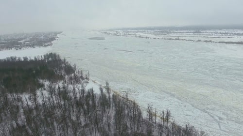 Aerial View of Frozen River Surrounded By Forest in Winter Season