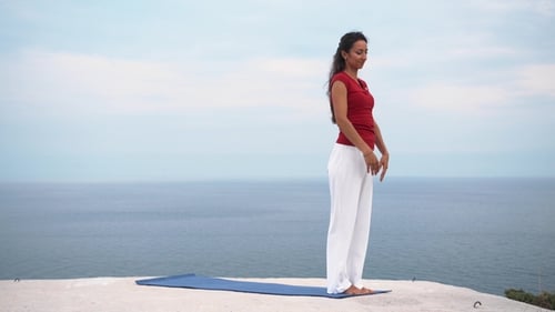 Young Slim Female Doing Yoga Warrior Pose Near the Sea