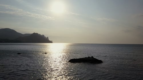 Flying Backward Over the Sea Surface with Rocks and Stones at Sunrise