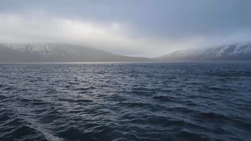 Panoramic View Mountain with Snowy Peaks in Blue Sea and Cloudy Sky Background