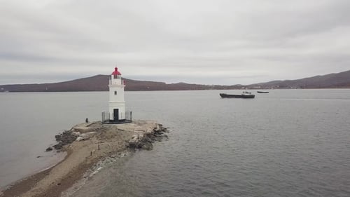 Drone View Freighter Ship and Sea Lighthouse on Mountain and Skyline Background