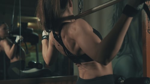 Fitness Woman Training with Weight-lifting Training Machine in Dark Gym