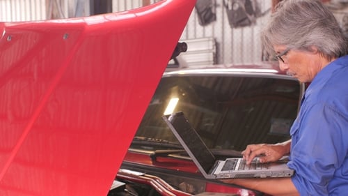 Mechanic Repairs the Damage Using the Pc Under the Hood in Car Service