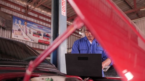 Mechanic Repairs the Damage Using the Pc Under the Hood in Car Service