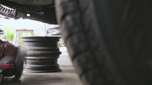 Mechanic Works Under Vehicle in Garage