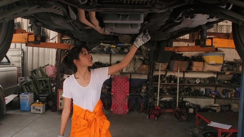 Young Beautiful Car Mechanic Inspects the Car Undercarriage Way in Garage