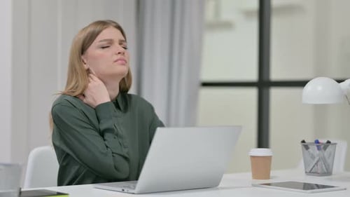 Woman Massaging Stiff Neck While Using Laptop