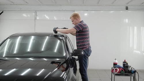 Side View of Man Using Device To Polish the Car Roof in Garage