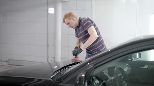 Worker Is Polishing Black Car Hood in an Auto Service