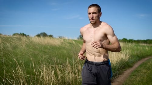 Portrait of a Muscular Shirtless Man Running Across the Field