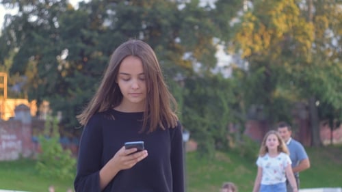 Girl Walking and Writing Messages on a Phone in the Street