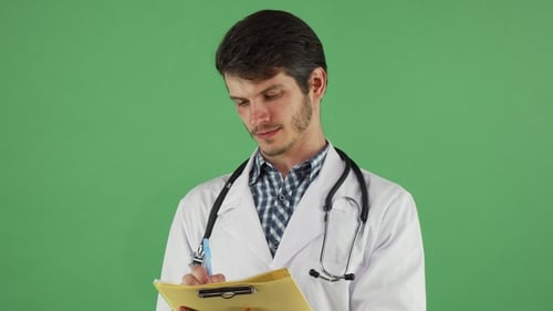 Young Male Doctor Writing on His Clipboard on Green Chromakey