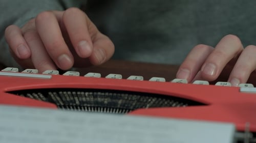 Hands Typing on Red Vintage Typewriter Keyboard