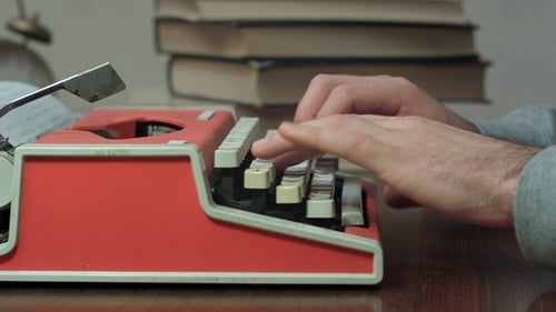 Man Typing on Vintage Red Typewriter on Desk