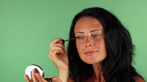 Beautiful Mature Woman Applying Makeup on Green Chromakey