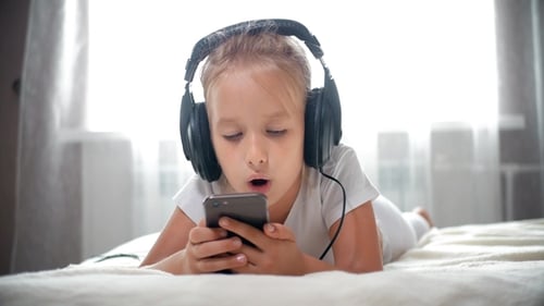 Happy Child Listens to Music with Headphones