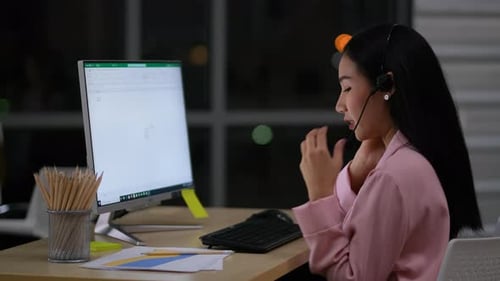 Vue latérale d'une jolie femme d'affaires travaillant la nuit en tant que centre d'appels ou opératrice et discutant avec le client