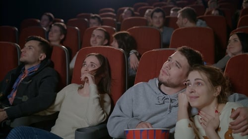 Love Couples Watching Movie in Cinema. Young Couple Embracing in Movie Theater