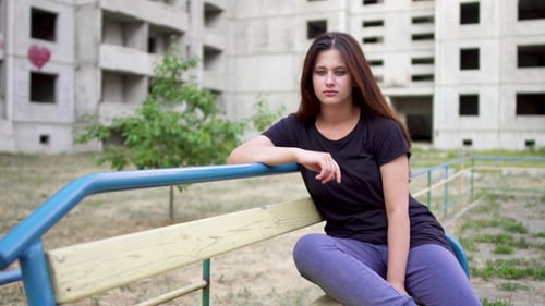 Nervous Brunette Girl Is Sitting Near High Building